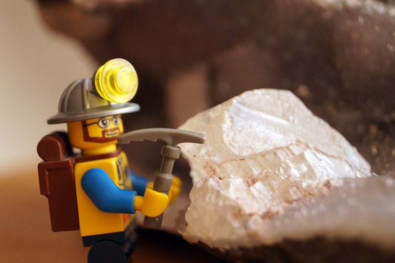 Foto zeigt eine Legofigur, die mit einer Spitzhacke an einem Mineral arbeitet