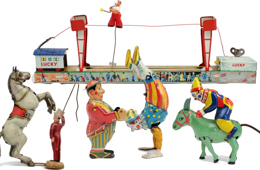 Foto mehrerer Zirkus-Blechspielzeuge, darunter drei Clowns, ein Pferde-Dompteur sowie ein Äffchen beim Seilklettern