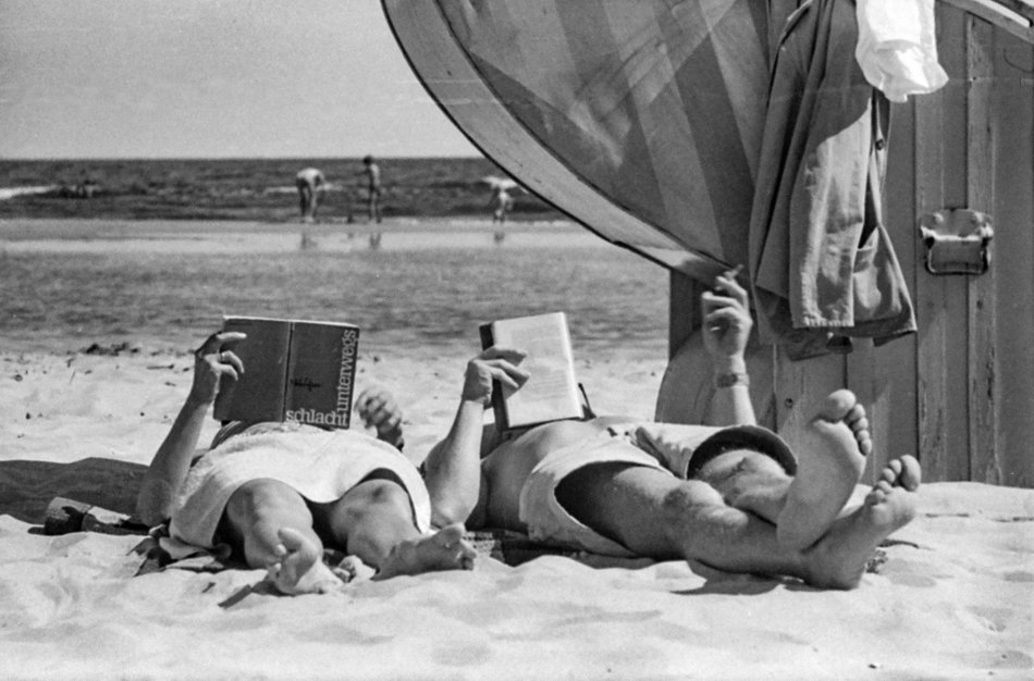 Schwarzweißfoto aus dem Sommer 1962: Irgendwo an der Ostsee. Eine Frau liest die 1962 in der DDR veröffentlichte Übersetzung des sowjetischen Romans „Schlacht unterwegs“ von Galina Nikolajewa