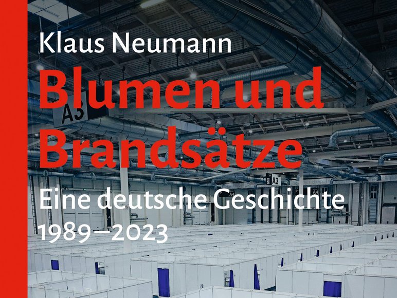 Auf dem Cover ist der Innenraum eines großen Aufnahmelagers zu sehen, darüber stehen der Autorenname, Klaus Neumann, sowie Titel und Untertitel des Buches, „Blumen und Brandsätze. Eine deutsche Geschichte, 1989 bis 2023“.
