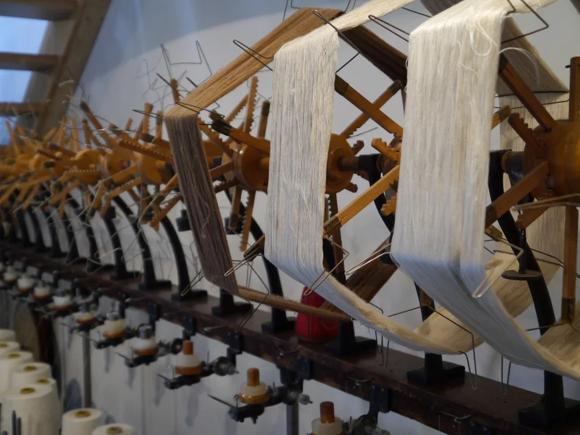 Das Foto zeigt eine Nahaufname einer historischen Flaschenspulmaschine, die zum Spulen von Garn diente.