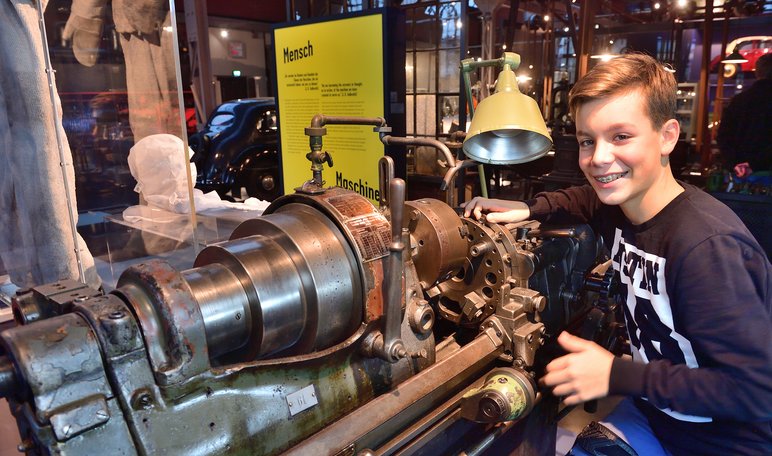 Ein Schüler legt in der historischen Schlosserwerkstatt der Dauerausstellung Hand an eine alte Maschine an.