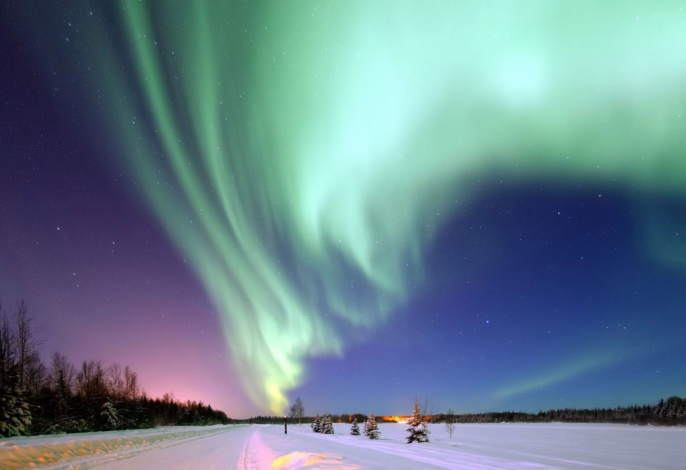 Polarlichter Über einer verschneiten Winterlandschaft erleuchten hellgrüne Polarlichter den Nachthimmel.