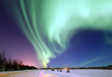 Polarlichter Über einer verschneiten Winterlandschaft erleuchten hellgrüne Polarlichter den Nachthimmel.