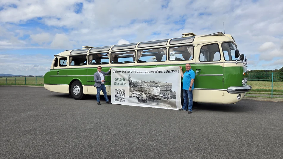 120 Jahre erste Buslinie Sachsens Stefan Löwe und Ulrich Reichel zeigen ein Werbebanner vor einem historischen Bus Ikarus 55.