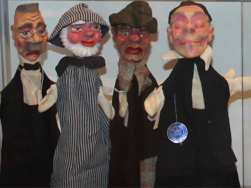 vier historisch anmutende Handpuppen, unter anderem eines Seemanns und eines Pfaffen