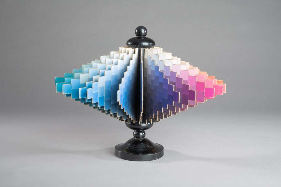 Farbmusterfächer in Spiralform auf schwarzem Ständer, Verlauf von Blau zu Rosa