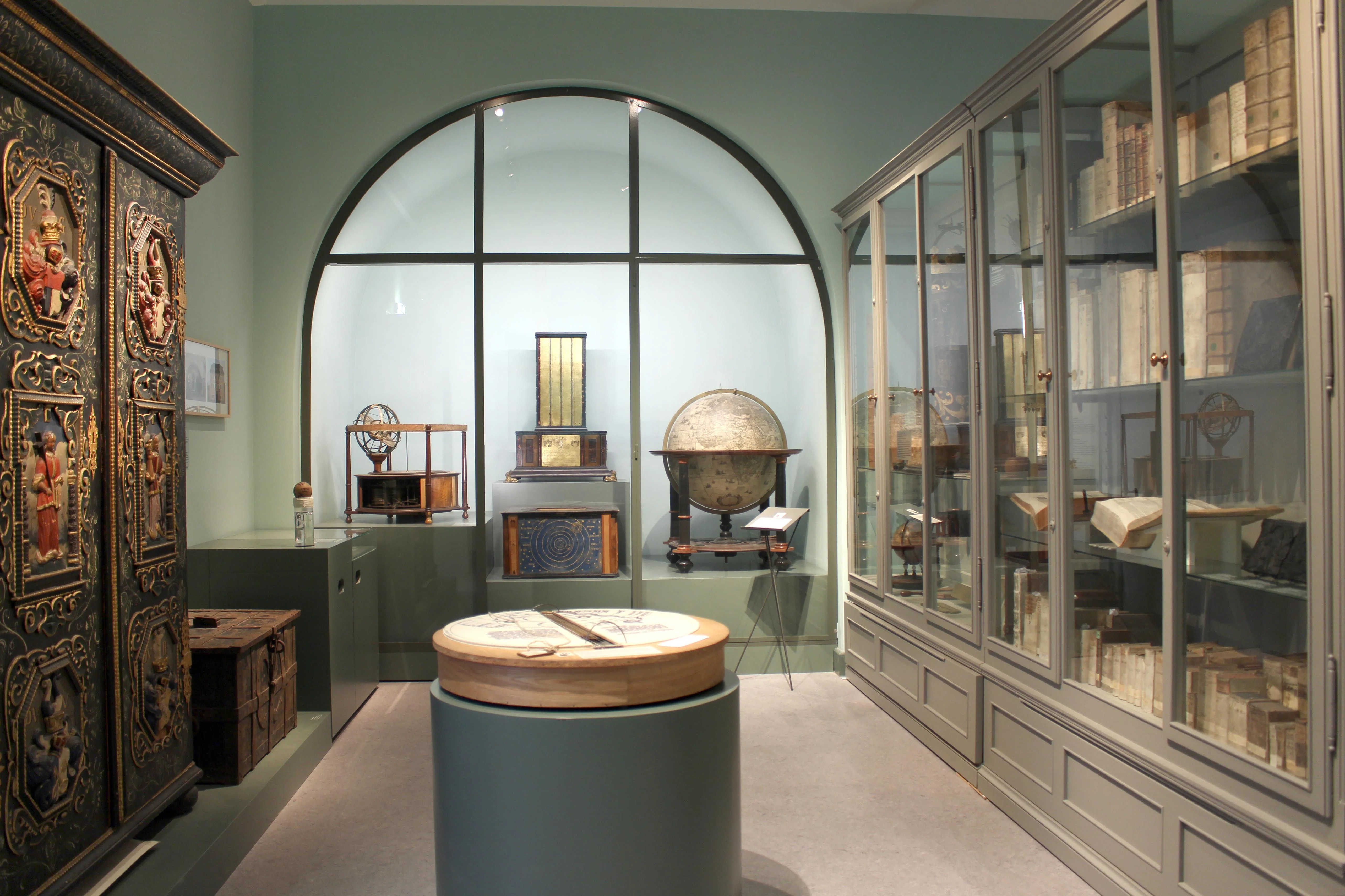Ein Raum im Museum Bautzen mit verschiedenen Vitrinen mit Büchern, astronomischen Geräten und historischem Schrank mit Truhe