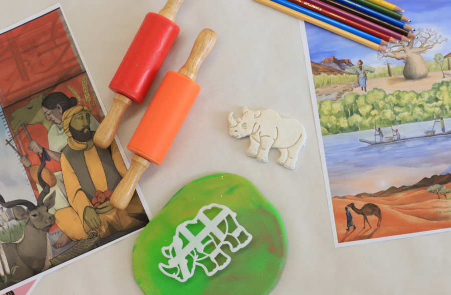 Atelier Africa Auf einer Tischplatte liegen verschiedene Bastelmaterialien: Teigrollen, ausgerollte Knete, Buntstifte, eine Nashorn-Ausstechform sowie ein ausgestochenes Nashorn.