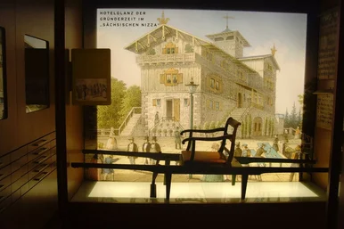 Wandtext: "Hotelglanz der Gründerzeit im 'Sächsischen Nizza'" mit Wandbild eines reich verzierten Gebäudes, davor eine Sänfte