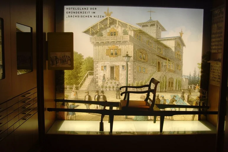 Wandtext: "Hotelglanz der Gründerzeit im 'Sächsischen Nizza'" mit Wandbild eines reich verzierten Gebäudes, davor eine Sänfte