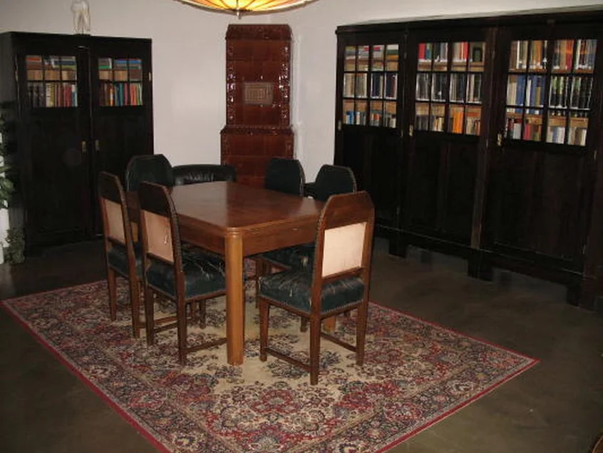 In einem mit historischen Bücherschränken bestückten Raum steht mittig ein Tisch mit sechs Stühlen.