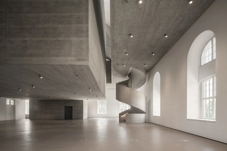 Leerer Ausstellungsbereich im Inneren des Gebäudes mit imposanter Wendeltreppe