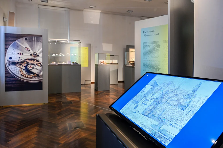 Installation der Denkmalentwürfe für Moritz Grossmann von 1914 In einem Ausstellungsbereich steht ein Bildschirm mit einer Videopräsentation der historischen Denkmal-Entwürfe.