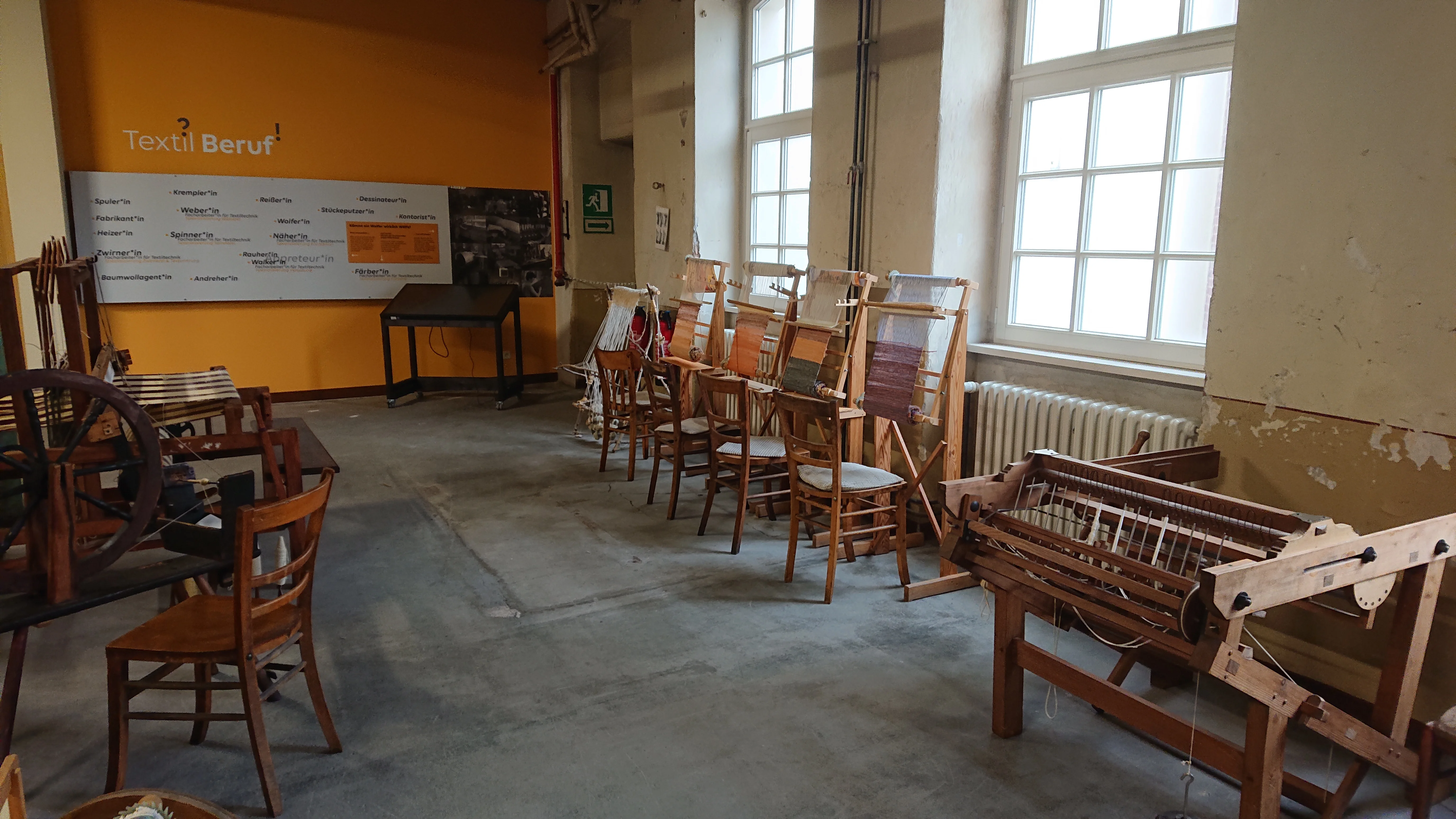 Blick in den Workshopraum in der ehemaligen Weberei Entlang der Fensterfront stehen Handwebrahmen und Sitzgelegenheiten für die Workshopteilnehmer