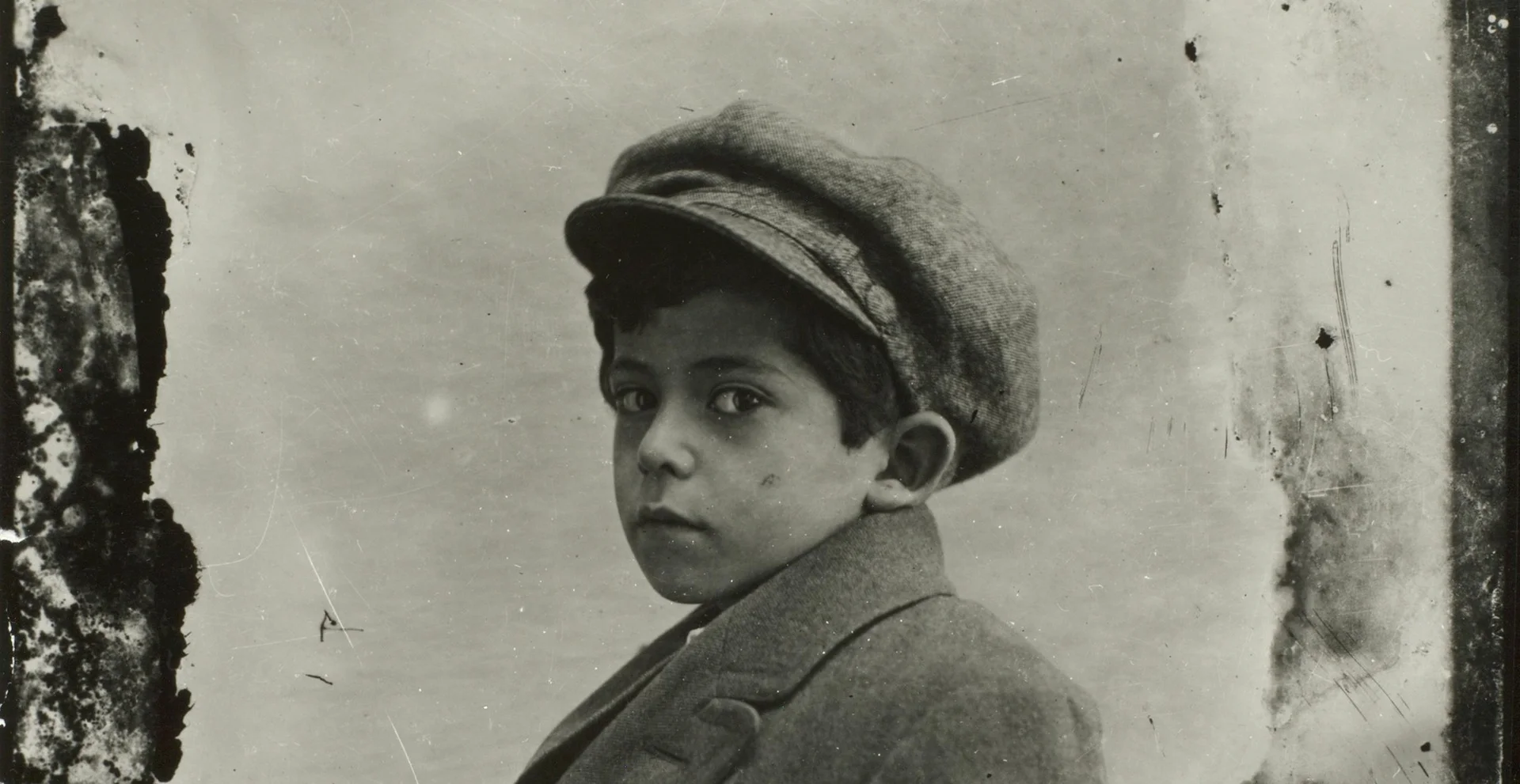 Sigi Mittelmann als Kind, 1924 Historisches Porträtfoto eines Jungen mit Hut, der direkt in die Kamera schaut. Das Foto ist in Schwarzweiß.