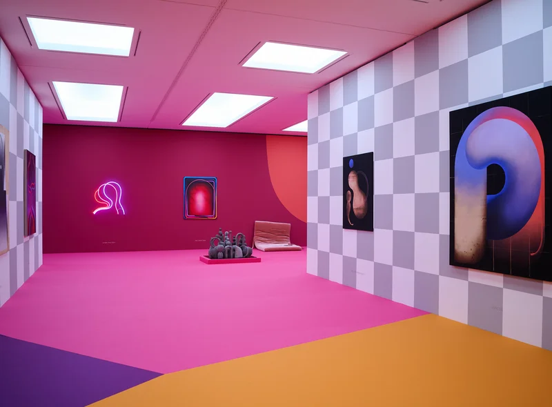 Blick in den Ausstellungsraum mit pinkem Fußboden und pinker Rückwand, seitlich weiß-grau gekachelte Wände mit Gemälden