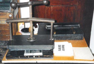 Alte Druckpresse Das Foto zeigt eine alte Druckpresse und ein bedrucktes Papier.