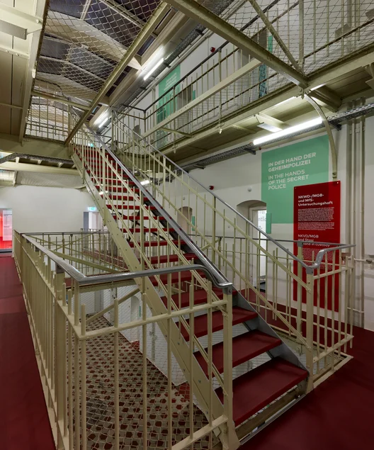 Zu sehen sind Eisengeländer, eine Freitreppe und Eingänge einstiger Gefängniszellen.