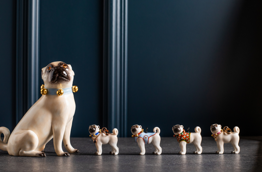Mops Das Bild zeigt fünf Porzellanfiguren, links ein größerer Mops und daneben vier kleine Möpse in einer Reihe.