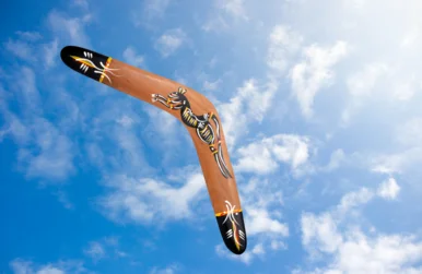 Ein mit einem galoppierenden Pferd und Ornamenten verziertes Wurfholz fliegt durch die Luft.