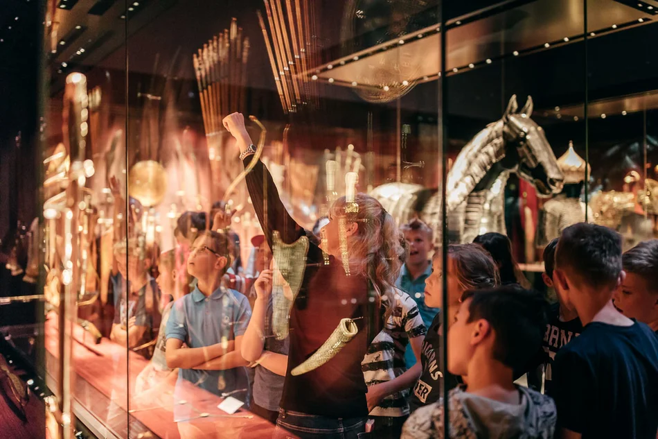 Schülerinnen und Schüler in der Türckischen Cammer Eine Museumspädagogin erklärt einer Kindergruppe Objekte in einer Vitrine.