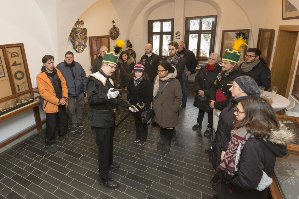 Weihnachtstradition Ein Mann in traditioneller erzgebirgischer Bergmanns-Uniform zeigt Gästen im Erzgebirgsmuseum historisches Bergbau-Werkzeug.