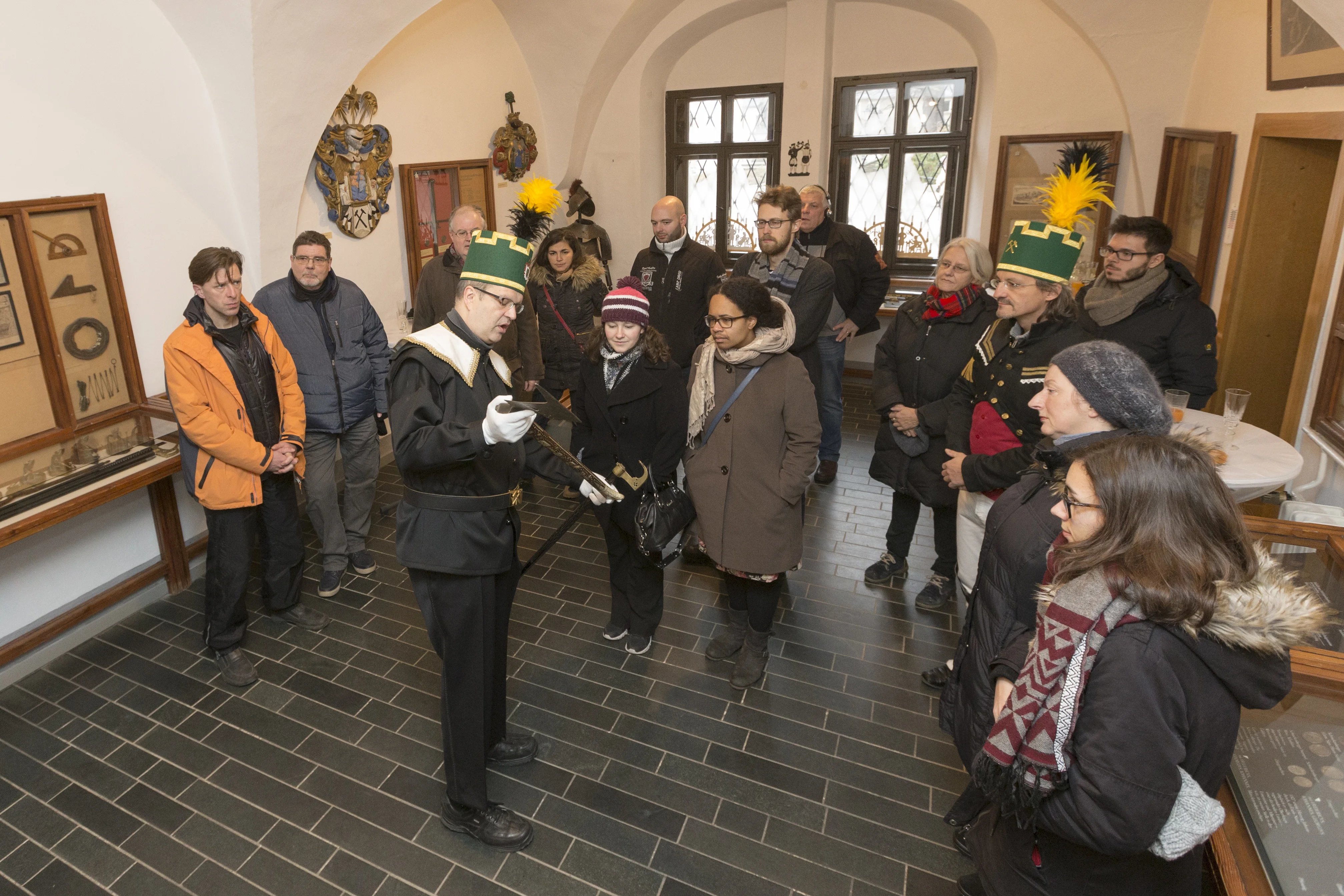 Weihnachtstradition Ein Mann in traditioneller erzgebirgischer Bergmanns-Uniform zeigt Gästen im Erzgebirgsmuseum historisches Bergbau-Werkzeug.