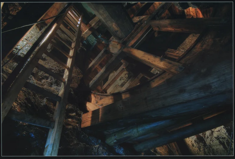 Ein Wasserrad in einem Stollen, daneben eine Leiter aus Holz