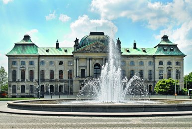 Sommerliche Außenansicht des Japanischen Palais, eines historischen Sandsteingebäudes, davor ein großer Platz mit Fontäne.