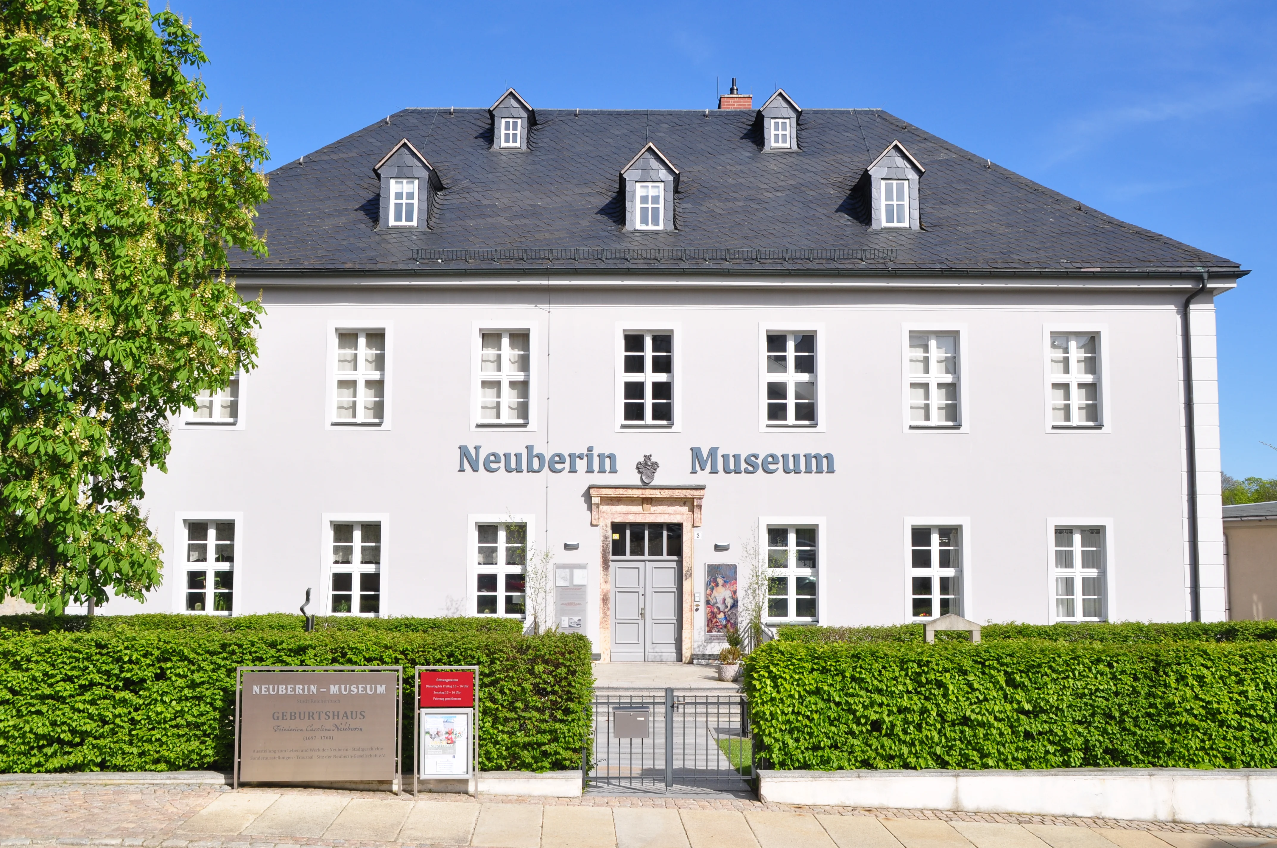 Zweistöckiges Gebäude mit dem Schriftzug "Neuberin Museum", weißer Fassade und einem schiefergedeckten Dach mit Gauben