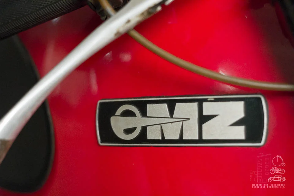 MZ ETS Detailaufnahme des Logos "eMZ" auf dem rot lackierten Tank eines Motorrads der Marke MZ.