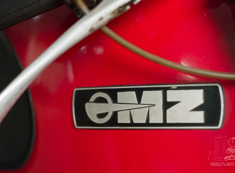 Detailaufnahme des Logos "eMZ" auf dem rot lackierten Tank eines Motorrads der Marke MZ.
