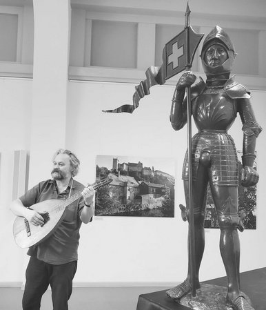 Museumspädagoge Ulrich Schollmeyer erklärt die Welt der Ritter Ein Laute spielender Mann steht neben einer Ritterrüstung