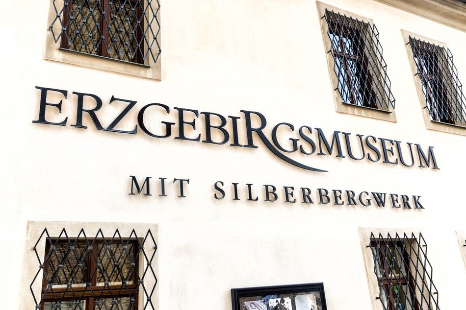 Das Foto zeigt die weiße Fassade eines historischen Gebäudes mit dem Schriftzug „Erzgebirgsmuseum mit Silberbergwerk“.
