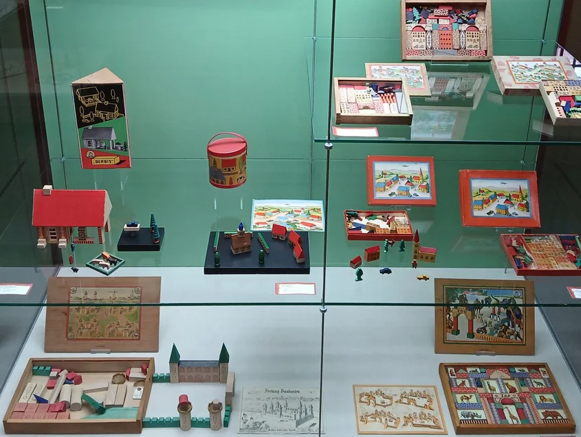 Festungs-, Dorf- und Zoobaukästen sind in einer Vitrine angeordnet.