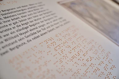 Nahaufnahme einer taktilen Station, der sogenannten Kohleninsel, mit Text in Schwarzschrift und Brailleschrift