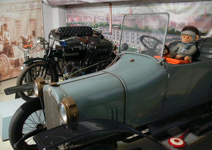 Ein Plüschaffe sitzt im historischen Kinderauto.