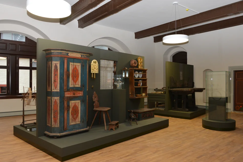 In einem Ausstellungsraum stehen historische Bauernmöbel, darunter ein bemalter Schrank.