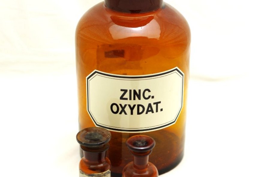 Drei historische Apotheker-Fläschchen aus braunem Glas, die größte ist etikettiert mit den Worten "Zinc Oxydat".