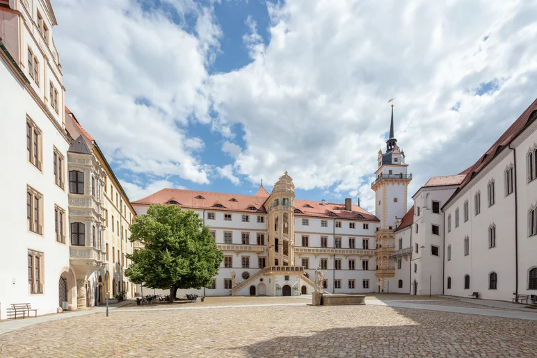 Sommerliche Ansicht des weitläufigen Innenhofes von Schloss Hartenfels mit Schlossflügeln im Renaissance-Stil zu Linken, zur Rechten und Geradeaus