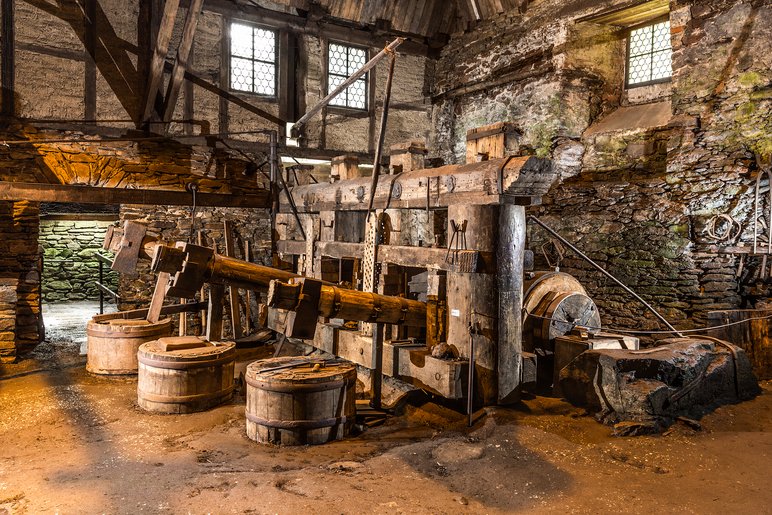 Historische Schmiede mit riesigen Hämmern in einem alten Gebäude mit Natursteinmauern