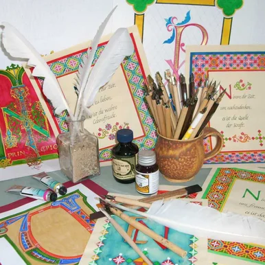 Kalligraphiekurs im Wilhelm Ostwald Park Neben bemalten und kunstvoll beschriebenen Papieren stehen Tuschegläschen sowie Gefäße mit Schreibfedern und Stiften.