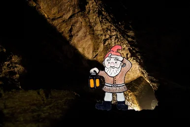 Im Reich des kleinen Bergzwergs Collage, in der die Zeichnung eines Wichtels mit roter Mütze und Laterne auf das Foto eines Bergbaustollens gesetzt wurde