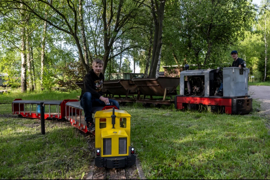 Zoll- und Feldbahn Zwei kleine Eisenbahnzüge fahren auf Schienen über eine Wiese.