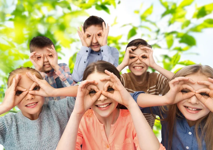 Kinder bilden mit den Händen Ferngläser vor ihren Augen und blicken uns an.