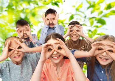Kinder bilden mit den Händen Ferngläser vor ihren Augen und blicken uns an.