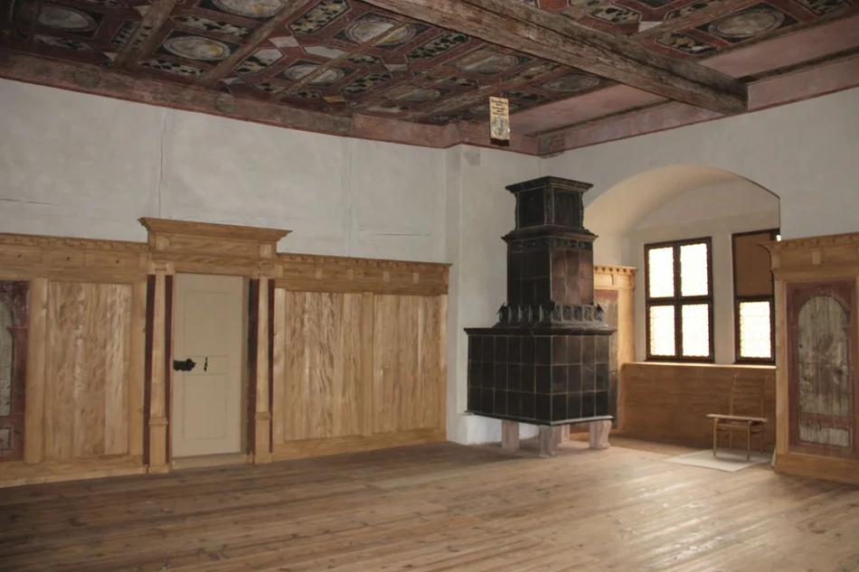 Rote Stube Die "Rote Stube" hat eher die Größe eines Saales. Sie ist holzvertäfelt und verfügt über eine dekorativ bemalte Holzbalkendecke. In einer Ecke steht ein historischer, dunkler Kachelofen.