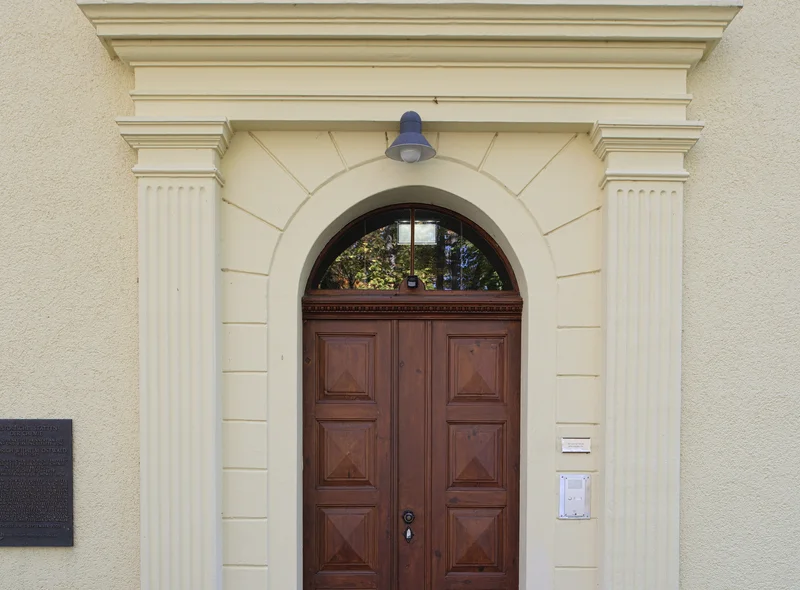 Portal eines Gründerzeitgebäudes mit neoklassizistischen Säulen zu beiden Seiten der Holztür und der Inschrift "Haus Energie"