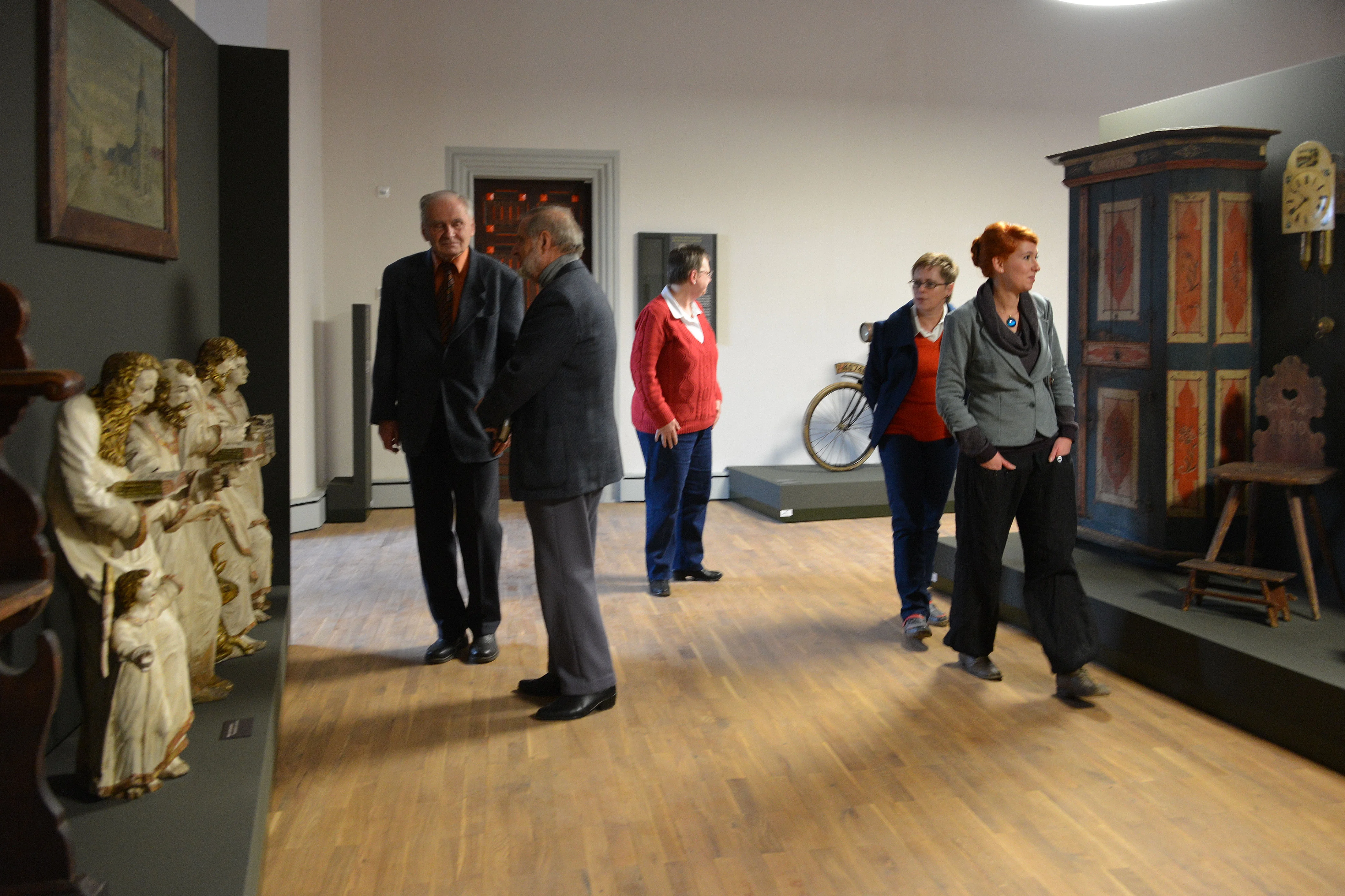 Dauerausstellung Museum Burg Mylau Menschen wandeln durch einen Raum mit Skulpturen sakraler Kunst sowie bemalten Möbeln.